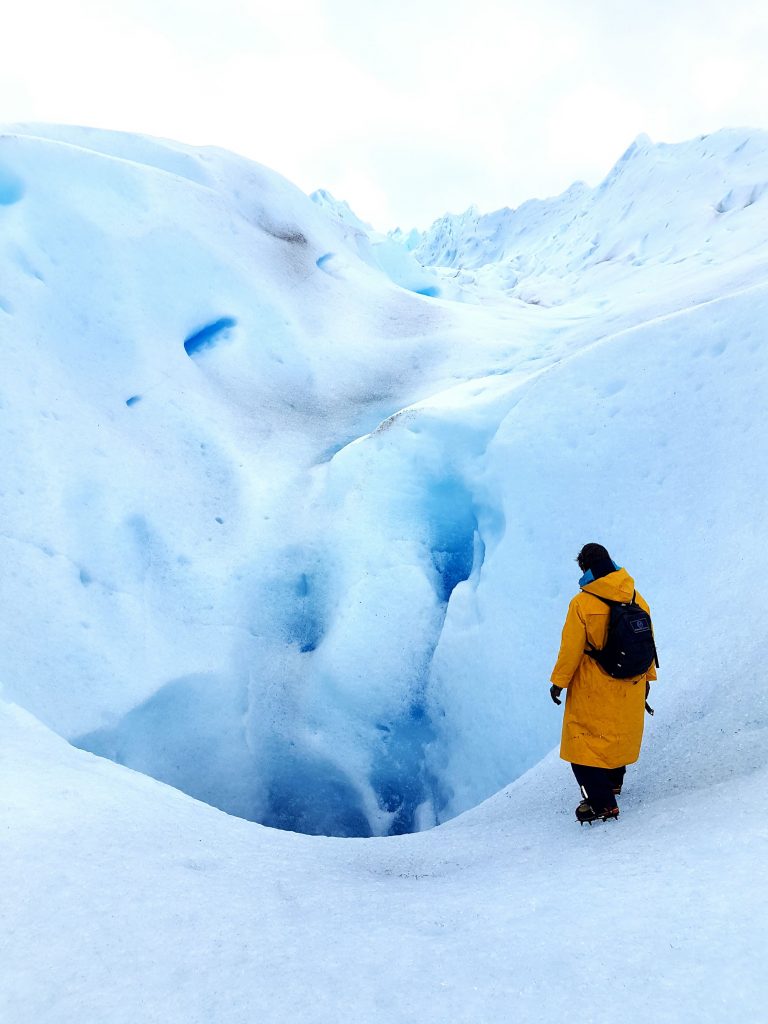 Gletscherspalte mit Frau im Vordergrund - Der Klimawandel und das Reisen.