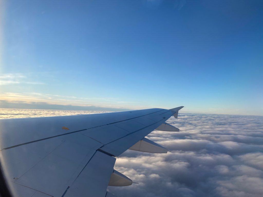 Blick aus dem Flugzeug auf den Flügel über den Wolken. Flugreise während Corona.