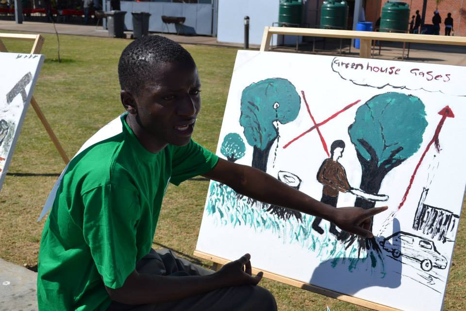 Junger Mann erklaert mit Bild den Klimaschutz - GruenerFliegen Spendenaktion mit UNICEF